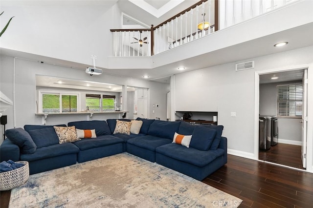 living room featuring visible vents, a high ceiling, wood finished floors, washer and dryer, and baseboards