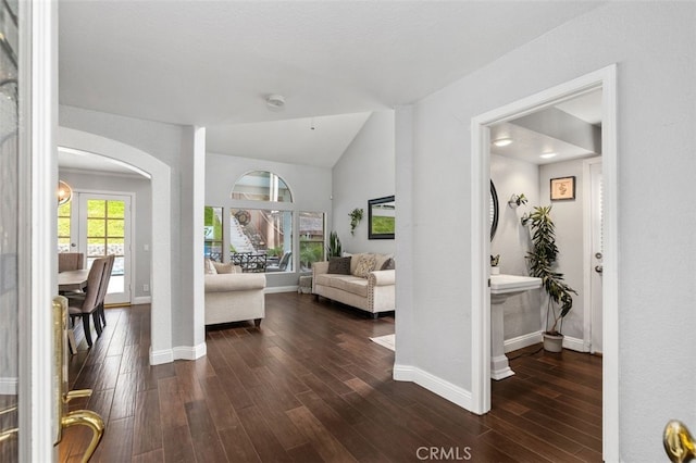 entryway with lofted ceiling, baseboards, arched walkways, and dark wood finished floors