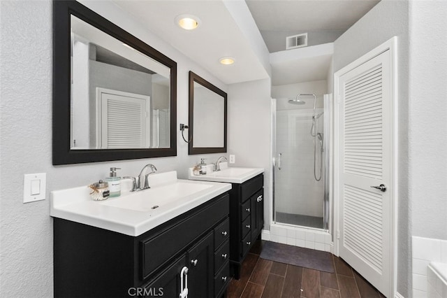 bathroom featuring a stall shower, wood tiled floor, visible vents, and a sink