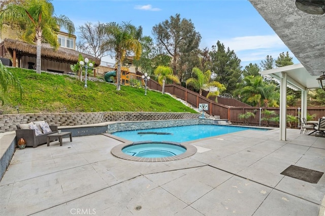 view of pool with an in ground hot tub, a lawn, a patio area, and a fenced backyard