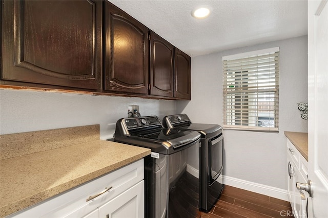 clothes washing area with dark wood-style flooring, cabinet space, a textured ceiling, independent washer and dryer, and baseboards