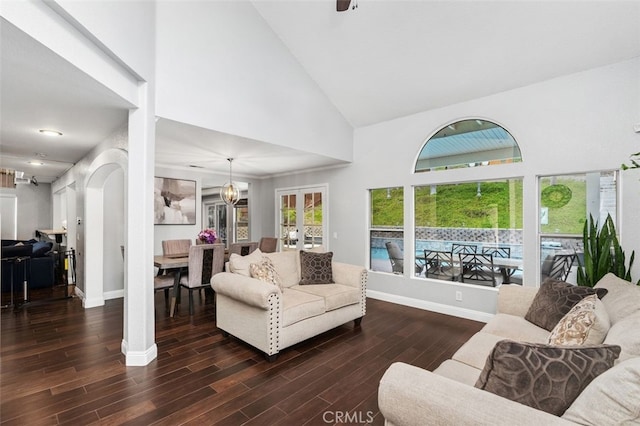 living area with baseboards, arched walkways, wood finished floors, french doors, and high vaulted ceiling