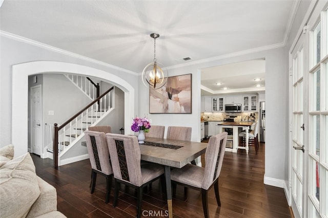 dining area featuring arched walkways, dark wood-style flooring, crown molding, and stairway