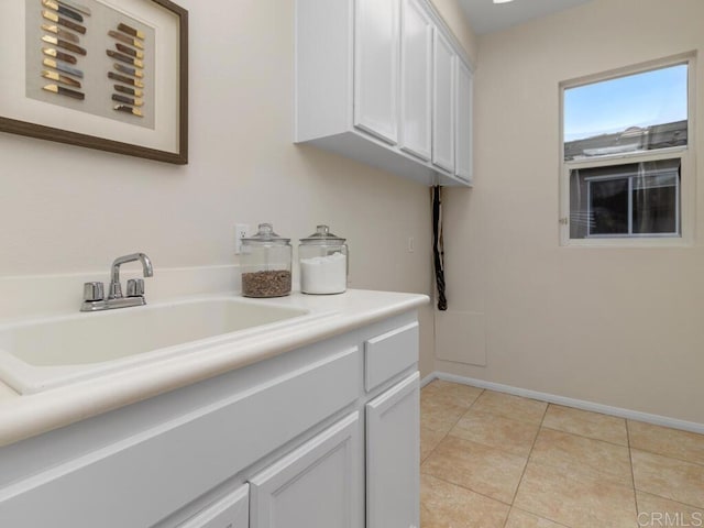 washroom with a sink, baseboards, and light tile patterned floors