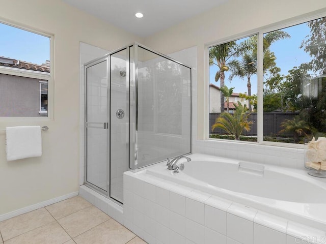 bathroom featuring a bath, a shower stall, baseboards, and tile patterned flooring