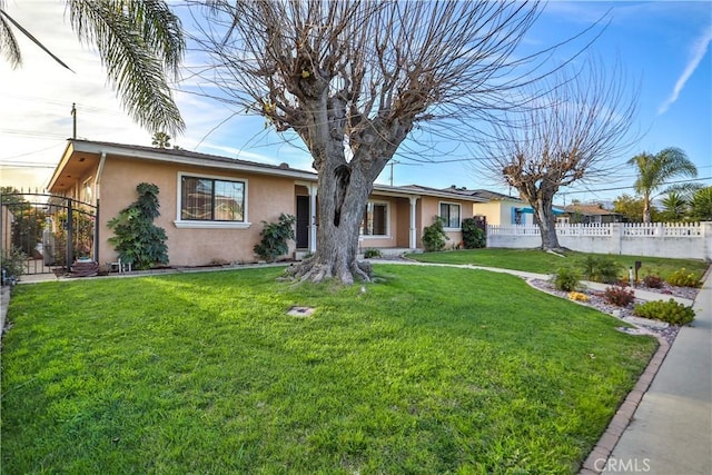 ranch-style home featuring a front yard, fence, and stucco siding