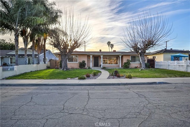 view of front of house featuring a yard, fence, and stucco siding