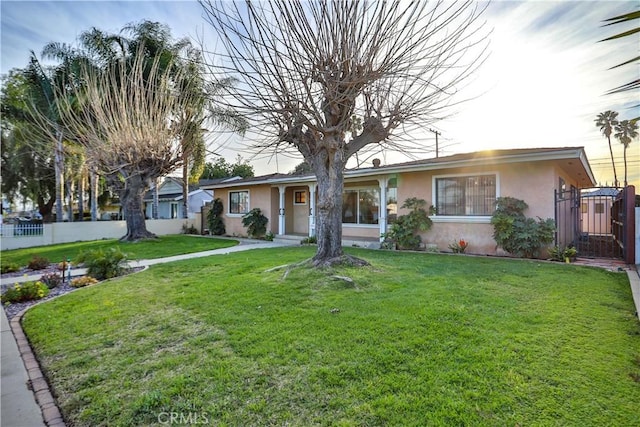 ranch-style home with a front yard, fence, and stucco siding