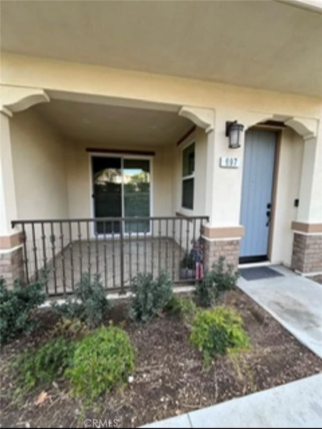 entrance to property featuring a porch and stucco siding