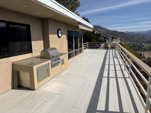 wooden deck with a mountain view, exterior kitchen, and area for grilling