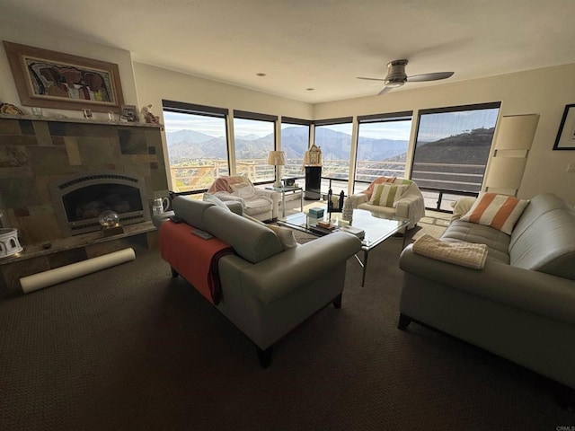 living room featuring a tiled fireplace, a mountain view, ceiling fan, and carpet flooring