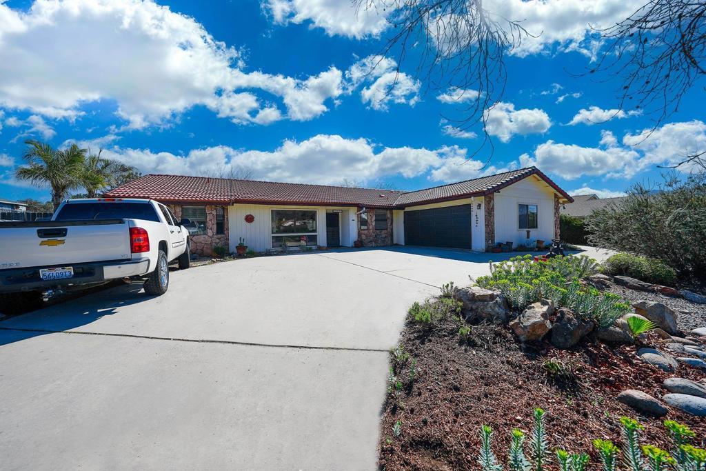 ranch-style house with a garage, concrete driveway, and a tiled roof