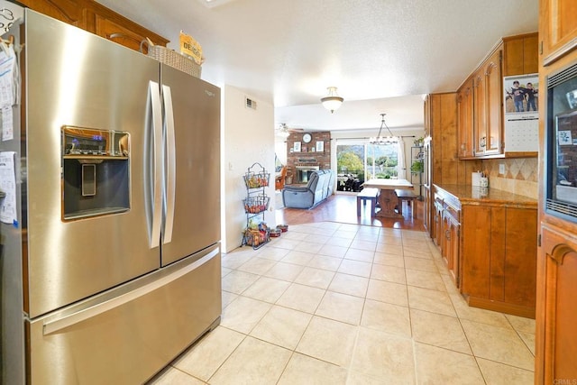 16233 Oakley Rd, Ramona, CA 92065 - kitchen featuring visible vents, brown cabinets, stainless steel refrigerator with ice dispenser, backsplash, and light tile patterned flooring