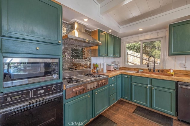 kitchen with wall chimney exhaust hood, dark wood-style flooring, a sink, stainless steel appliances, and green cabinetry