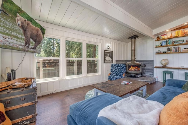 living room featuring a wood stove, wooden ceiling, wood finished floors, and beamed ceiling