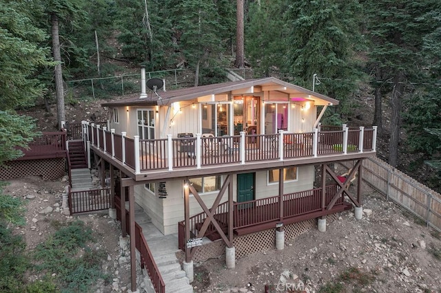 back of property with stairs, fence, and a deck