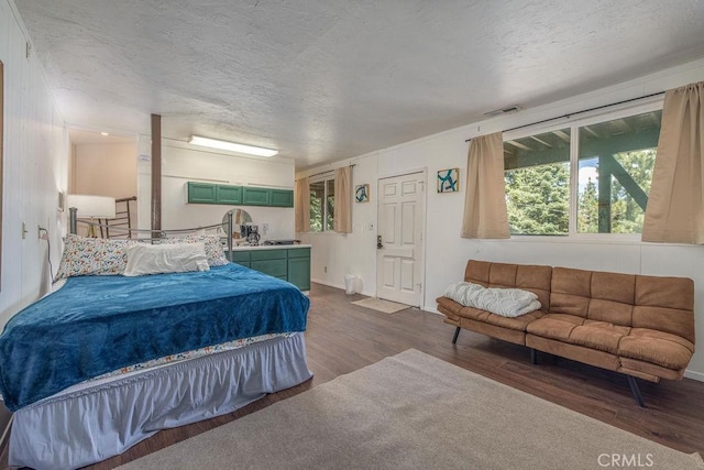 bedroom featuring dark wood-style floors, multiple windows, and a textured ceiling