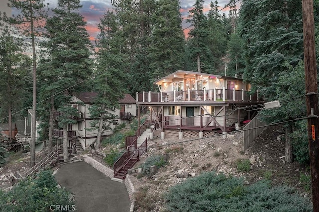 back of house at dusk with a deck and stairs