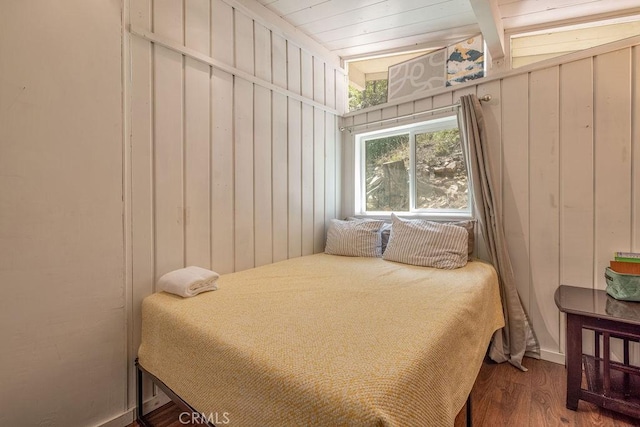 bedroom featuring wood finished floors and wooden walls