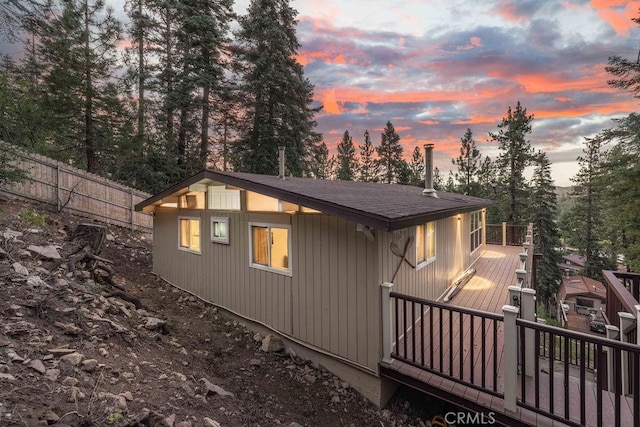 property exterior at dusk with fence and roof with shingles