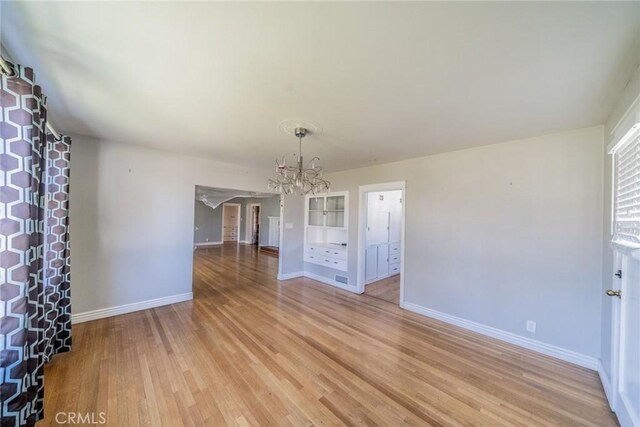 interior space with a chandelier, light wood finished floors, and baseboards