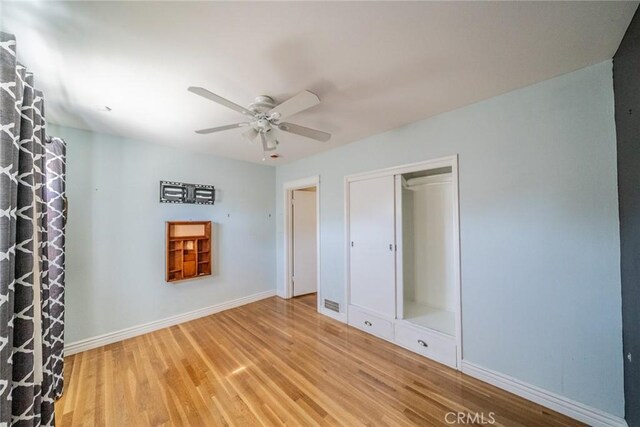 unfurnished bedroom with a ceiling fan, a closet, baseboards, and wood finished floors