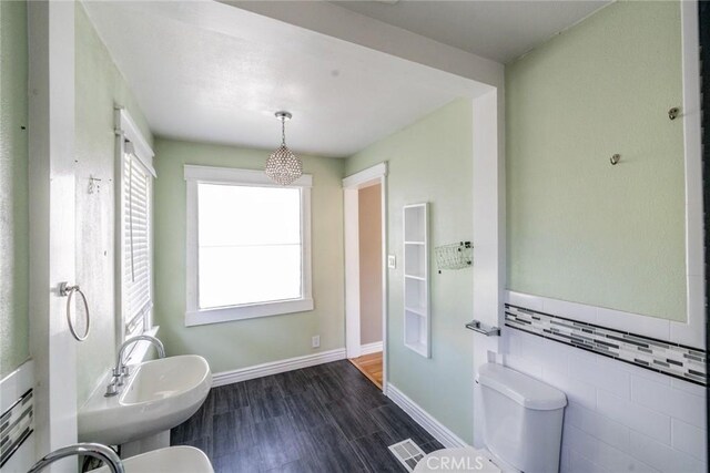 bathroom with a sink, tile walls, toilet, and wood finished floors