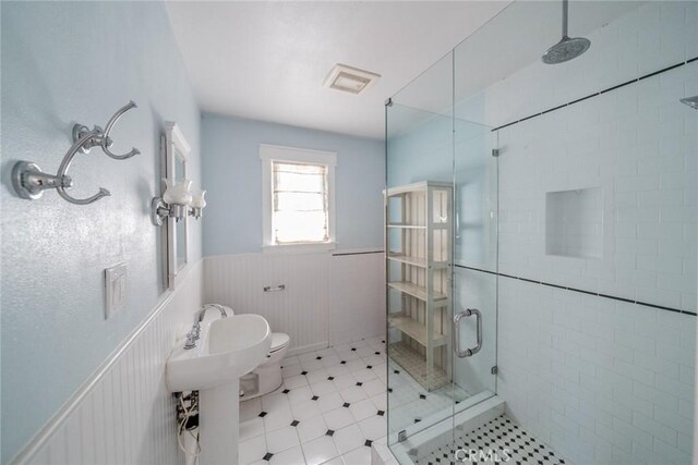 bathroom with a stall shower, wainscoting, visible vents, and toilet