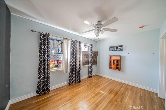 spare room with ceiling fan, wood finished floors, and baseboards