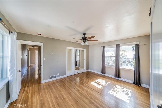 empty room with light wood finished floors, baseboards, visible vents, and ceiling fan