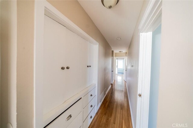 corridor with baseboards and wood finished floors