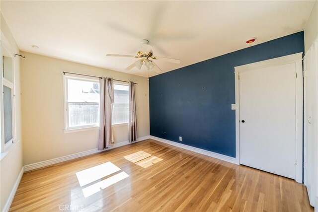 empty room featuring light wood-style flooring, baseboards, and ceiling fan