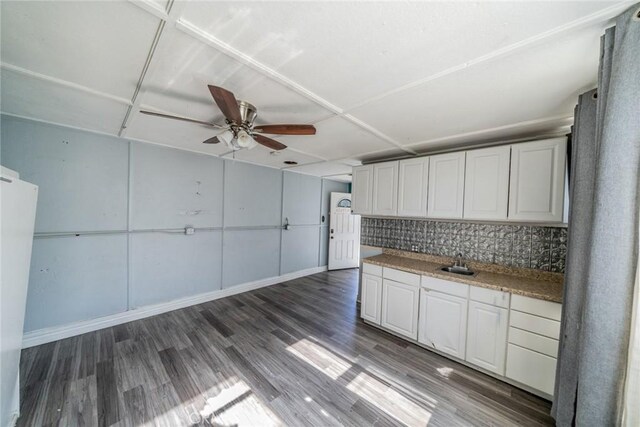 kitchen featuring white cabinets, ceiling fan, wood finished floors, a sink, and backsplash