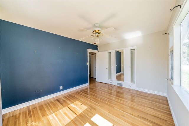 unfurnished bedroom with multiple windows, visible vents, baseboards, and wood finished floors