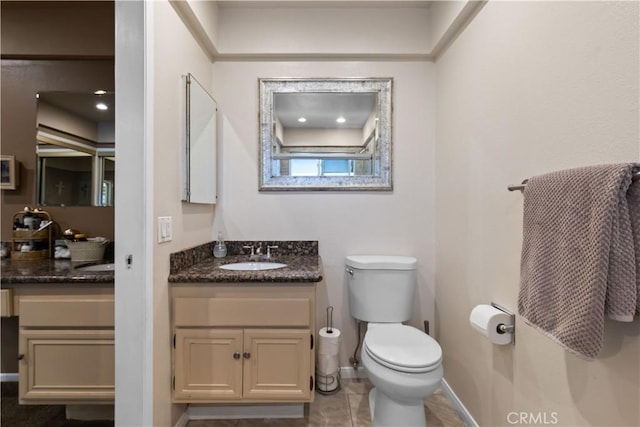 bathroom with toilet, tile patterned flooring, baseboards, and vanity