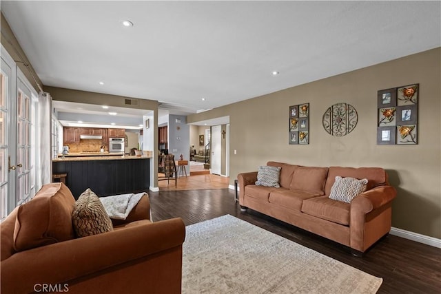 living area featuring dark wood-style floors, recessed lighting, visible vents, and baseboards