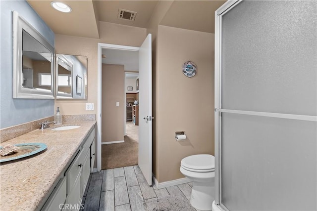 full bath with toilet, wood finish floors, a sink, visible vents, and double vanity