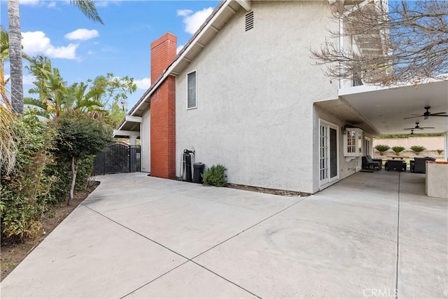 view of property exterior featuring a patio, a gate, a ceiling fan, and stucco siding