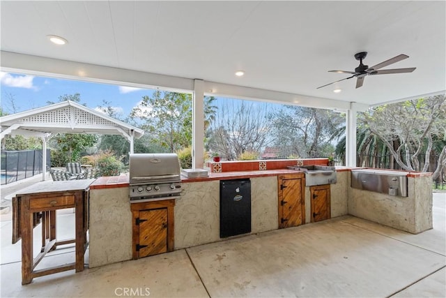 view of patio / terrace featuring area for grilling, ceiling fan, fence, exterior kitchen, and a gazebo