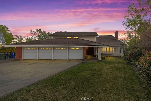 view of front of home with a garage, driveway, a yard, and a chimney