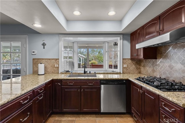 kitchen with a wealth of natural light, stainless steel dishwasher, under cabinet range hood, a sink, and black gas stovetop