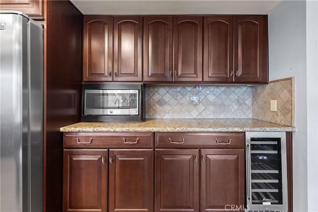 kitchen with appliances with stainless steel finishes, wine cooler, light stone counters, and decorative backsplash