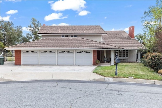 traditional-style home featuring driveway, a chimney, an attached garage, a front lawn, and brick siding