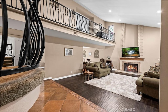 living room with recessed lighting, a high ceiling, a fireplace, wood finished floors, and baseboards