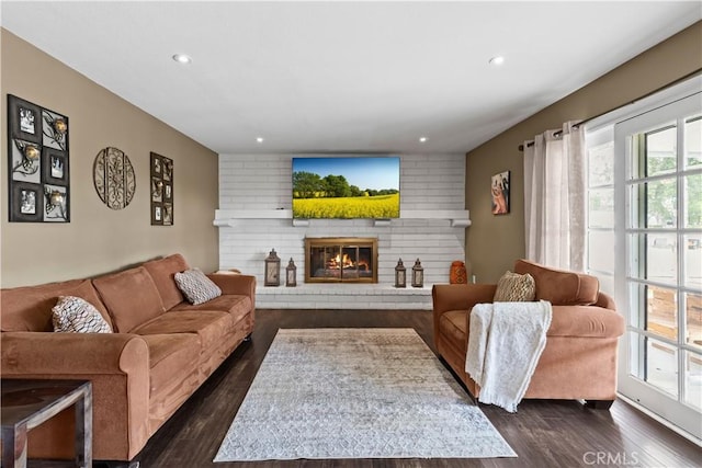 living area featuring a brick fireplace, dark wood finished floors, and recessed lighting