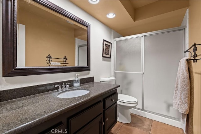 bathroom featuring toilet, a stall shower, vanity, and tile patterned floors