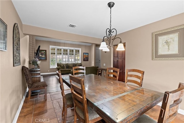 dining space with stone tile flooring, visible vents, baseboards, and an inviting chandelier