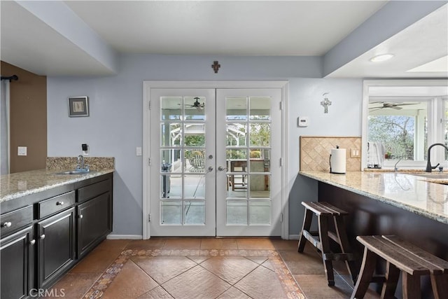 doorway to outside featuring a ceiling fan, french doors, a sink, and baseboards