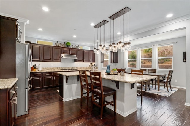 kitchen with dark wood-style flooring, a breakfast bar area, a center island with sink, and dark brown cabinetry