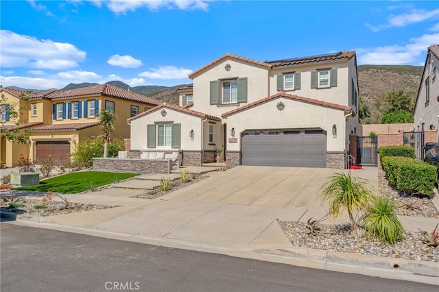 mediterranean / spanish-style home featuring a garage, concrete driveway, stone siding, fence, and stucco siding